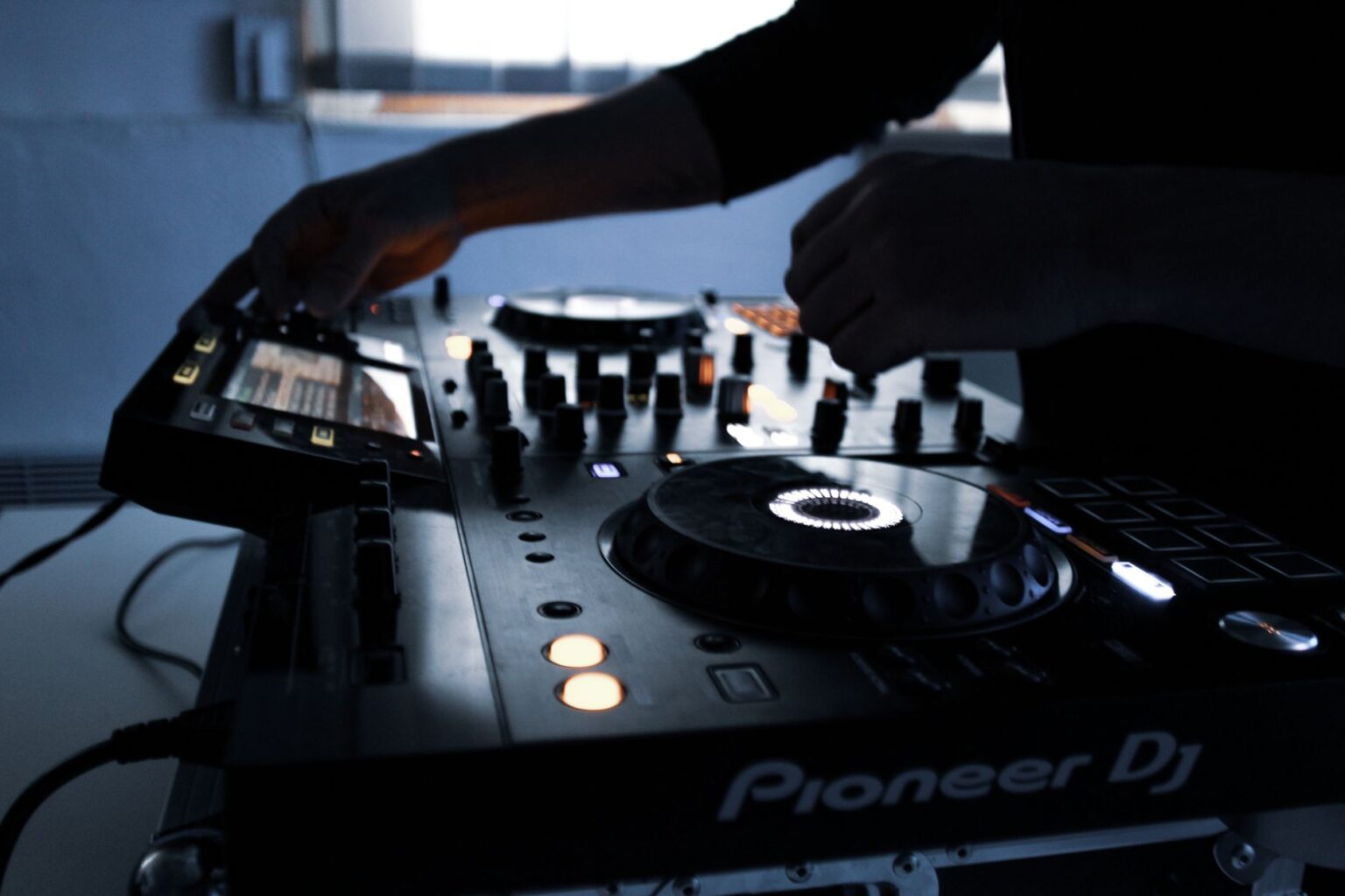DJ w ciemnym pokoju miksuje muzykę hardstyle na nowoczesnym sprzęcie Pioneer DJ
