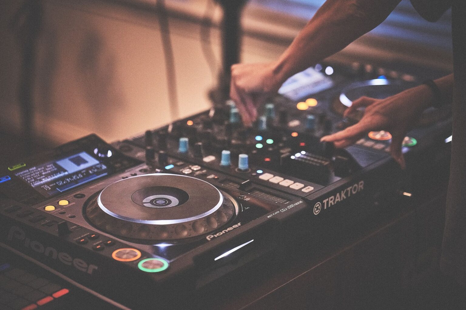 Ręce DJ-a obsługujące profesjonalny sprzęt muzyczny z konsolą i odtwarzaczami Pioneer w klubie