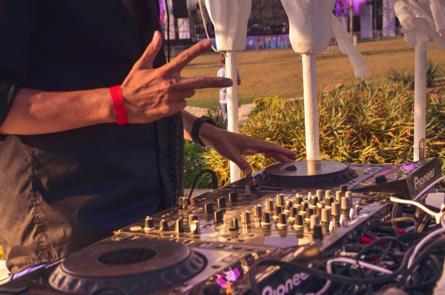 DJ miksuje muzykę hardstyle na festiwalu plenerowym, obsługując profesjonalną konsoletę Pioneer