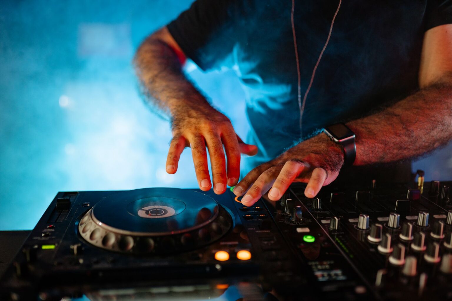 DJ Warface miksuje muzykę stojąc za profesjonalną konsolą w klubowym oświetleniu