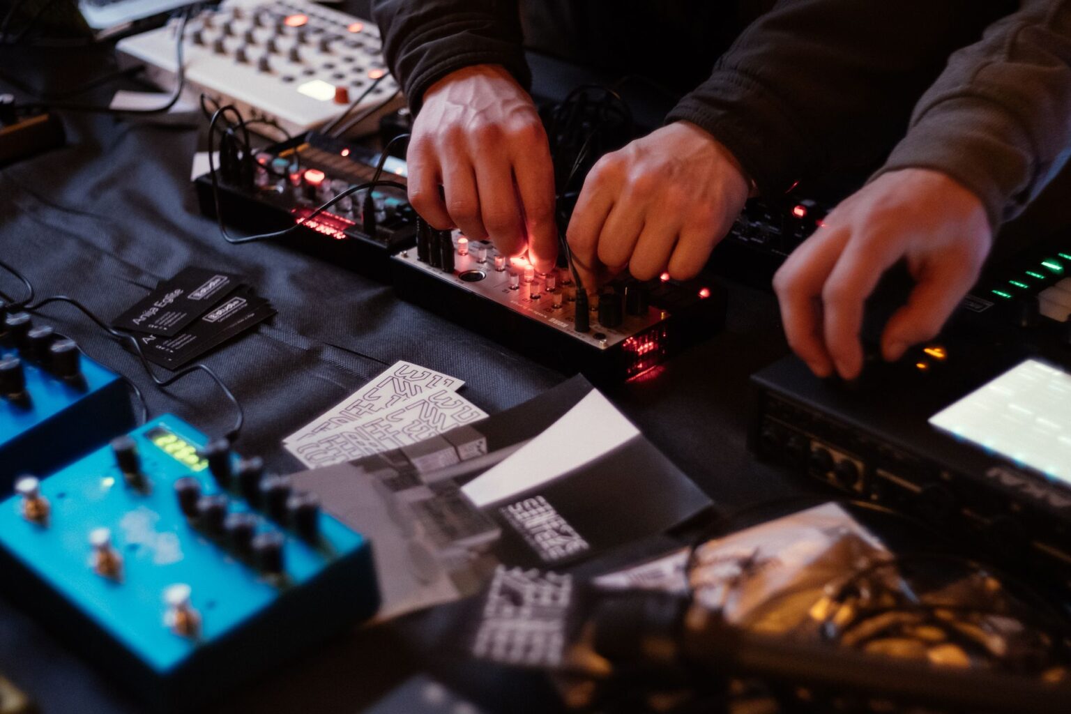 Jakie są najpopularniejsze syntezatory w hardstyle i hard dance? Muzyk obsługuje syntezator z migającymi diodami na stole zastawionym sprzętem muzycznym