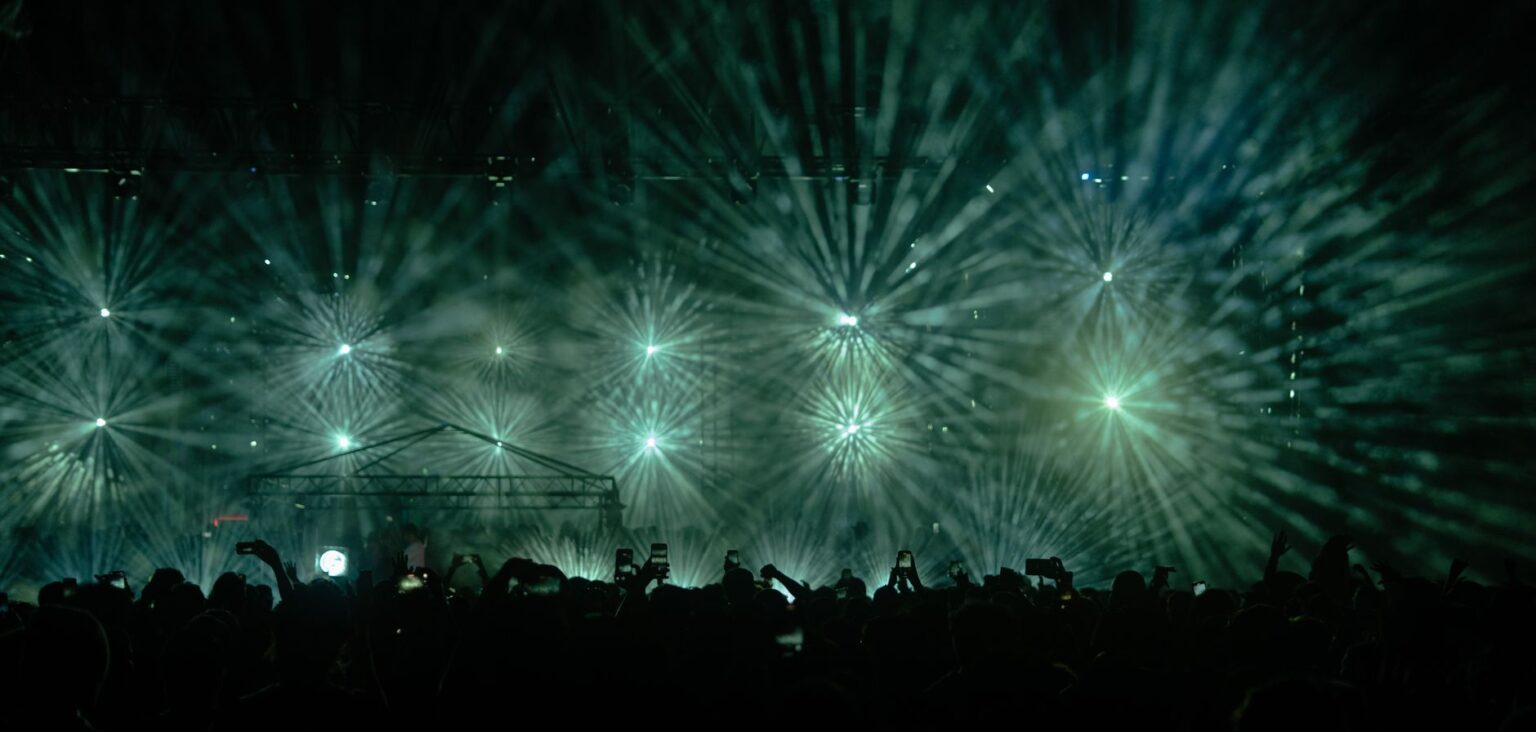 SYNDICATE 2023 / Official Aftermovie: obraz, muzyka i prawa do publikacji Tłum ludzi na koncercie SYNDICATE 2023 z podniesionymi telefonami w blasku zielonych świateł scenicznych